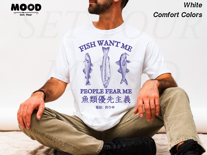 May include: White t-shirt with a blue graphic of three fish and the text "FISH WANT ME PEOPLE FEAR ME". The shirt also includes Japanese text. The shirt is made of a comfortable material.