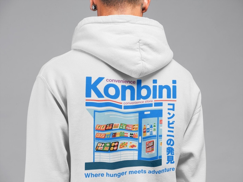 May include: White hoodie with a blue and red graphic on the back. The graphic features the word "Konbini" above an illustration of a convenience store with Japanese text and the phrase "Where hunger meets adventure."