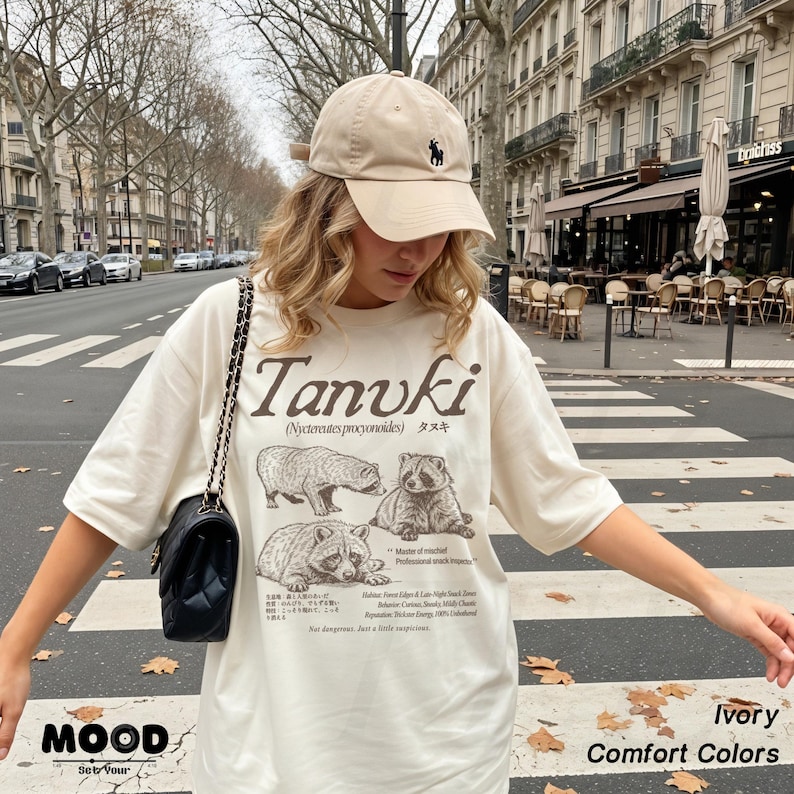 woman wearing ivory tanuki t-shirt with japanese raccoon dog graphic, vintage wildlife design on comfort colors tee, styled in street outfit outdoors