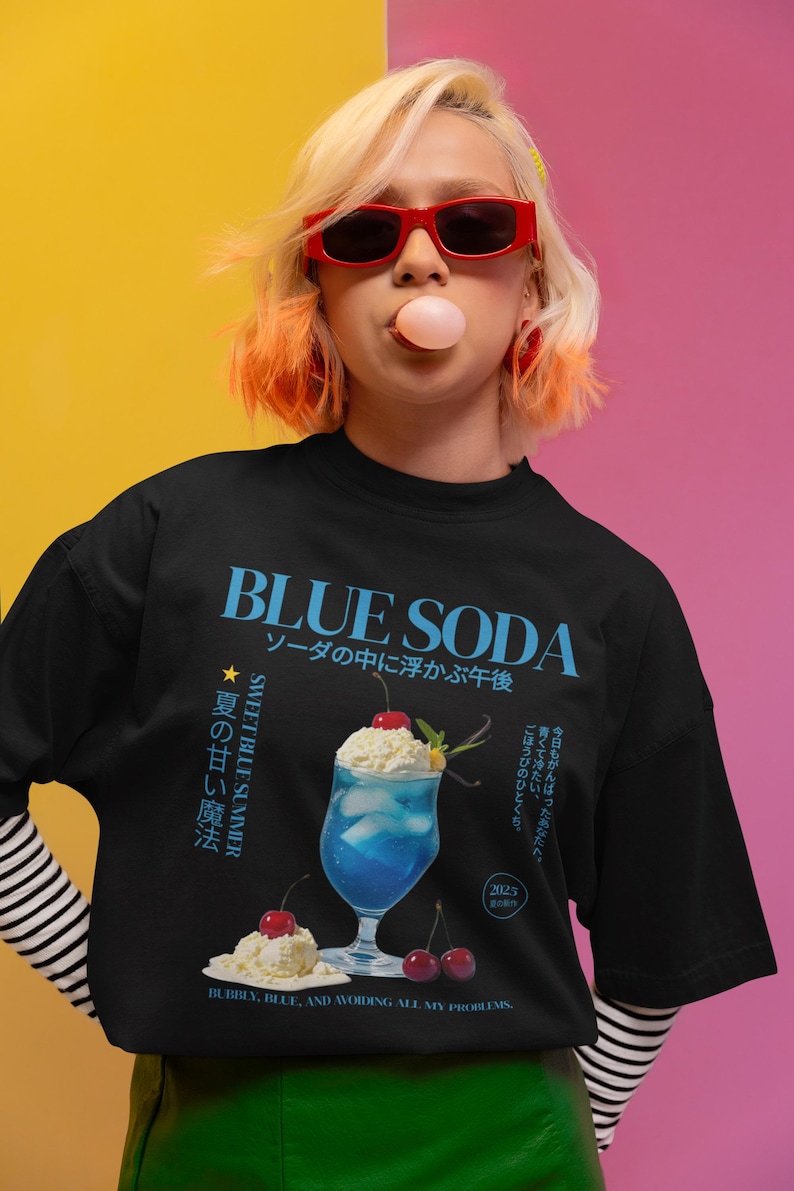 May include: Black t-shirt with a blue graphic that says "BLUE SODA" and Japanese text. The graphic features a blue drink with whipped cream and cherries. The shirt also has the text "SWEET BLUE SUMMER".