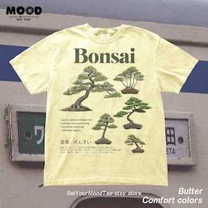 May include: Butter-colored t-shirt featuring the word "Bonsai" above illustrations of bonsai trees. The shirt includes text about bonsai cultivation and the Etsy store name. The shirt is part of the "Comfort Colors" collection.