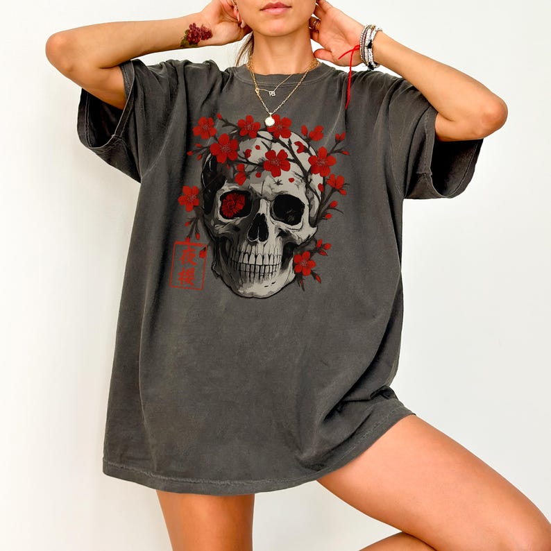 Pepper Comfort Colors T-shirt featuring a Japanese skull design surrounded by red cherry blossoms. Harajuku streetwear tee with gothic floral art and vintage wash.
