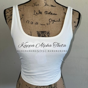 Può includere: Top bianco a costine con la scritta "Kappa Alpha Theta SDSU" stampata sul davanti.
