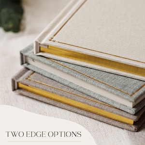 May include: Three stacked books with fabric covers in cream, light grey, and tan. The top two books feature gold-gilded page edges and a thin gold border on the cover. The bottom book has classic white page edges. Text reads: TWO EDGE OPTIONS.