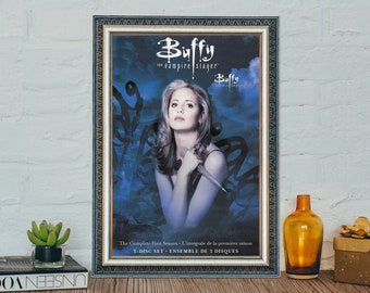 Puede incluir: Un póster enmarcado para la serie de televisión "Buffy, la cazavampiros". El póster presenta un fondo azul y morado con una mujer de cabello oscuro sosteniendo un cuchillo. El texto en el póster dice "Buffy, la cazavampiros" y "The Complete First Season - L'intégrale de la première saison 3-DISC SET - ENSEMBLE DE 3 DISQUES".