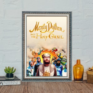 May include: A framed poster for "Monty Python and the Holy Grail". The title is in gold script. The image depicts characters in medieval costumes, with a central figure wearing a crown. The background has a warm, sunset-like hue.