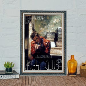 Könnte beinhalten: Ein gerahmtes Filmplakat für den Film Fight Club mit Edward Norton und Brad Pitt. Das Plakat hat einen abgenutzten, Vintage-Look mit weißem Hintergrund und schwarzem Text. Das Plakat ist in einem silbernen Rahmen mit schwarzem Passepartout gerahmt.