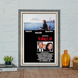 May include: A framed movie poster for the film "Working Girl" starring Harrison Ford, Melanie Griffith, and Sigourney Weaver. The poster features a black background with the film title in red and white text. The poster also includes a scene from the film with Harrison Ford and Melanie Griffith.