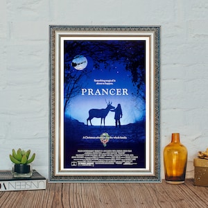 May include: A movie poster for the film "Prancer", a Christmas adventure for the whole family. The poster features a silhouette of a reindeer and a young girl against a dark blue night sky with a crescent moon.