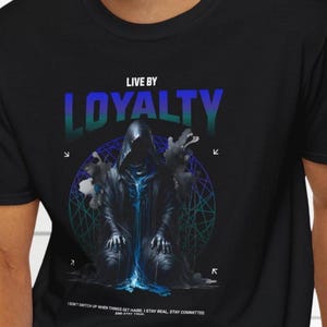 Può includere: T-shirt nero con una figura incappucciata inginocchiata davanti a un disegno geometrico. Il testo "LIVE BY LOYALTY" è sopra, con il testo "I DON'T SWITCH UP WHEN THINGS GET HARD..." sotto.