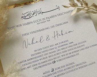 Könnte beinhalten: Eine weiße Karte mit goldenen Akzenten und schwarzem Text. Die Karte zeigt eine arabische Inschrift, den Text "UND WIR HABEN EUCH IN PAAREN ERSCHAFFEN AN-NABA 78:8" und die Namen "Vihal & Hakim". Die Karte enthält auch das Datum "21.04.2023" und den Text "IN DER STADT KIEL AM 21.04.2023, ENTSPRECHEND DEM 02. SHAWWAL 1444, UNTER ANWESENHEIT DES IMAMS, DES WALIS UND DER ZEUGEN GESCHLOSSEN WURDE, BEGLAUBIGT IHRE EHESCHLIEBUNG IMINKLANG MIT DEM ISLAMISCHEN RECHT, WIE ES IM KORAN UND DER SUNNA DES PROPHETEN VORGESCHRIEBEN IST."