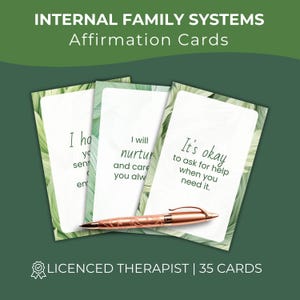 May include: A set of Internal Family Systems affirmation cards with a green leaf border design. The cards feature text including 'It's okay to ask for help when you need it.' A rose gold pen rests horizontally across the cards.