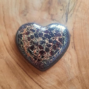 May include: A heart-shaped glass ornament with a dark blue and black base and gold glitter accents.
