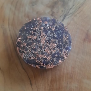 May include: A round, dark purple and copper-colored resin coaster with a glittery finish.