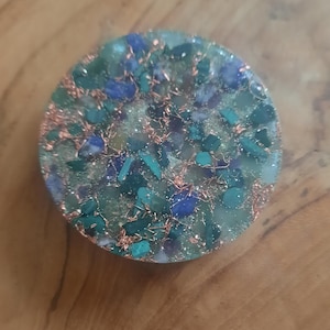 May include: A round, flat, green and blue crystal grid with copper wire and glitter embedded in clear resin.