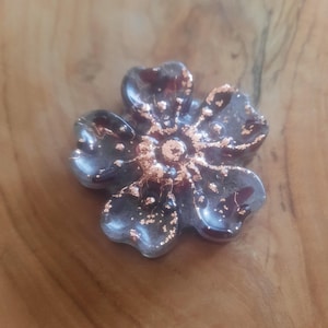 May include: A dark gray glass flower with a copper-colored center and flecks of copper throughout the petals.