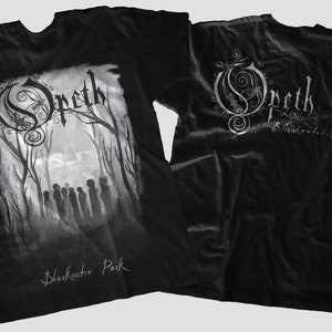 May include: Black t-shirt featuring the band Opeth's logo and album art for "Blackwater Park." The front design shows a grayscale forest scene with figures. The back displays the band's logo and album title in silver.