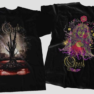 Op de afbeelding: Zwart T-shirt met een bandlogo op de voorkant en een grafisch ontwerp op de achterkant. Het ontwerp aan de voorkant toont een boom met een hand die uit het water reikt. Het ontwerp aan de achterkant toont het gezicht van een vrouw met een bloemmotief. De bandnaam "Opeth" is in gouden letters op beide kanten van het shirt geschreven.
