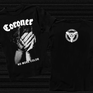 May include: Black t-shirt with a white graphic of a person with their hands covering their face. The text "Coroner" and "No More Color" are printed on the front of the shirt. The back of the shirt has a white graphic of a skull with horns.