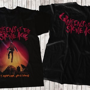 May include: Black t-shirt with a red graphic print of the band Queens of the Stone Age. The front of the shirt features a man jumping in front of a red and orange sunset. The back of the shirt has the band's name in red.