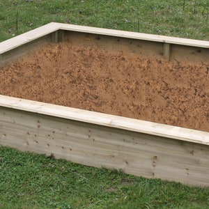 Könnte beinhalten: Ein rechteckiges, erhöhtes Gartenbeet aus Holz, gefüllt mit brauner Erde. Das Beet besteht aus unbehandelten Holzbrettern.