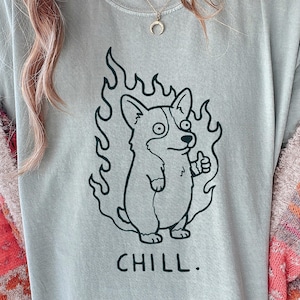 May include: A light blue t-shirt with a black graphic of a corgi dog surrounded by flames, giving a thumbs up. The word "CHILL." is printed below the dog.
