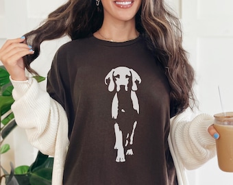 May include: A dark brown t-shirt with a white dog graphic. The dog is illustrated in a minimalist style. The t-shirt is part of a casual clothing range.