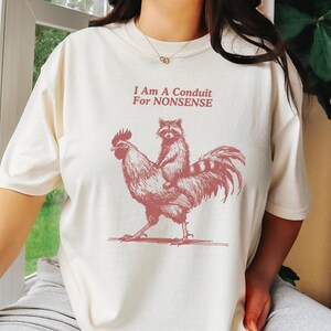 Lustiges Waschbär Reithahn T-Shirt - 'I Am A Conduit For Nonsense' Grafik T-Shirt - Humorvolles Animal Print Shirt - Unisex Größen
