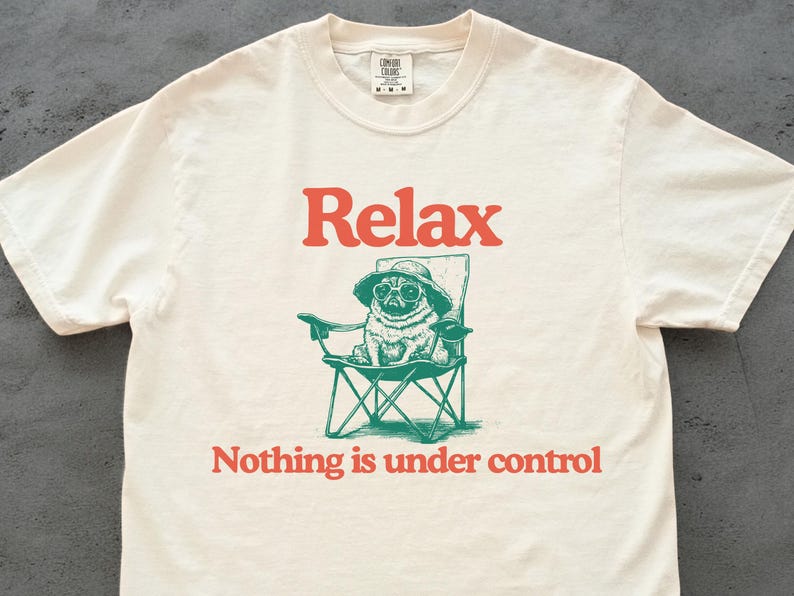 May include: Off-white t-shirt featuring the word "Relax" in orange above a green illustration of a pug in sunglasses and a hat, sitting in a folding chair. The text "Nothing is under control" is below.
