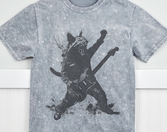 May include: A gray t-shirt with a distressed look features a black and white graphic of a cat playing an electric guitar.