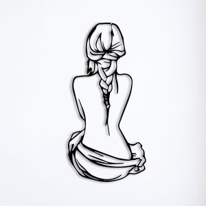 May include: Black metal wall art depicting a woman sitting with her back to the viewer, her hair in a braid. The art is mounted on a white wall.