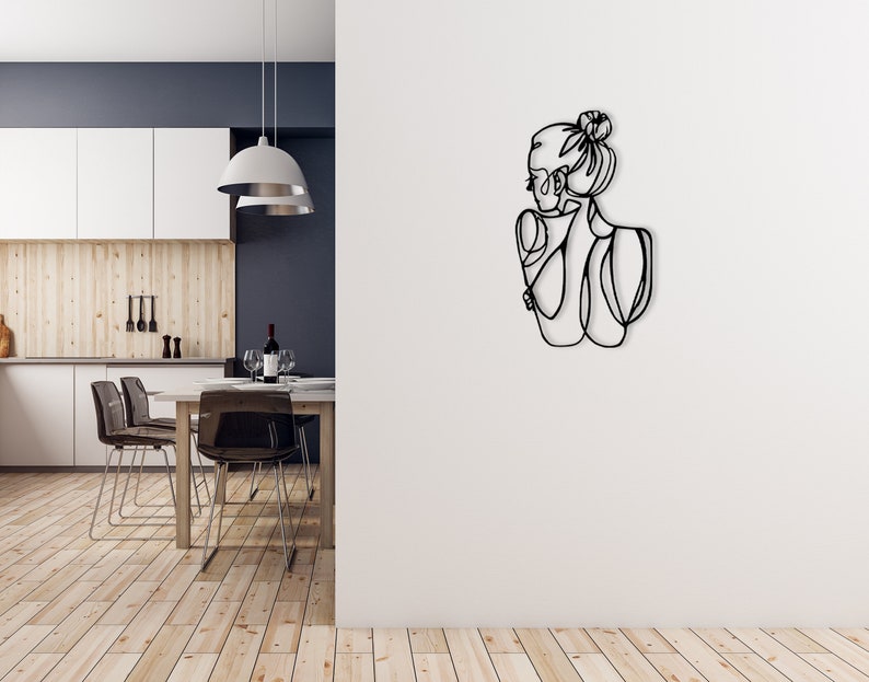 May include: Black metal wall art depicting a line drawing of a woman with her hair in a bun, facing away from the viewer.