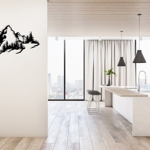 May include: A black metal wall art sculpture depicting a mountain range with trees. The sculpture is mounted on a white wall in a modern kitchen with a white countertop and a large window.