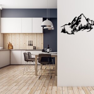 May include: A black metal wall art sculpture depicting a mountain range with trees. The sculpture is mounted on a white wall in a modern kitchen with a wooden floor and a dining table with chairs.