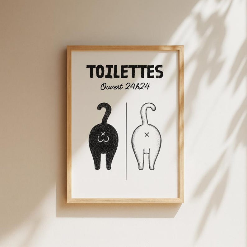 K&ouml;nnte beinhalten: Gerahmter Kunstdruck mit dem Wort "TOILETTES" &uuml;ber dem Text "Ouvert 24h24". Der Druck zeigt zwei stilisierte R&uuml;ckansichten von Katzen, eine schwarze und eine wei&szlig;e, getrennt durch eine vertikale Linie. Die Kunst ist in einem Holzrahmen.