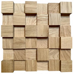 Op de afbeelding: Een wandpaneel gemaakt van natuurlijk hout met een 3D-ontwerp. Het paneel bestaat uit veel kleine vierkanten die in een willekeurig patroon zijn gerangschikt. De vierkanten zijn allemaal even groot en zijn gemaakt van lichtbruin hout.