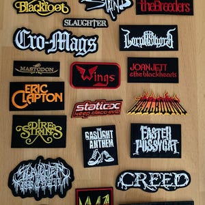 Op de afbeelding: Een verzameling bandpatches met verschillende rock- en metalbands, waaronder Blackfoot, the Breeders, Cro-Mags, Mastodon, Eric Clapton, Dire Straits, The Gaslight Anthem, Faster Pussycat, Creed, MMA en Jawbreaker.