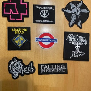 May include: A collection of embroidered patches featuring band logos and designs. The patches include the logos for Rammstein, Dream Theater, Machine Head, Alice in Chains, Opeth, and Falling in Reverse, along with a London Underground logo.
