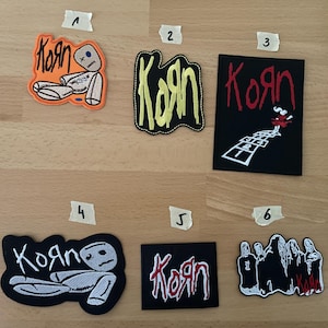 Puede incluir: Colección de seis parches bordados con la banda Korn. Los diseños incluyen el logotipo de la banda en varios estilos, una muñeca vudú y un gráfico de rayuela. Los parches son en negro, naranja y amarillo.