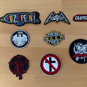 Puede incluir: Un conjunto de parches bordados con logotipos y símbolos de bandas musicales. Incluye parches con los nombres "Led Zeppelin", "Clutch" y "W.A.S.P.", junto con otros diseños en negro, rojo y blanco.
