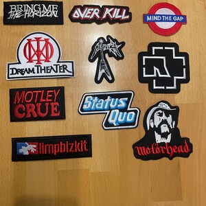 May include: A collection of embroidered patches featuring band logos and names. Patches include "Bring Me The Horizon," "Over Kill," "Dream Theater," "Motley Crue," "Status Quo," "Limp Bizkit," and "Motorhead." The patches are in various colors and shapes.