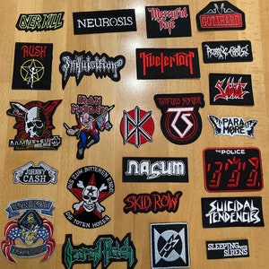 Könnte beinhalten: Eine Sammlung von aufgestickten Aufnähern mit verschiedenen Bandlogos und -namen. Die Aufnäher haben unterschiedliche Formen und Größen, mit einer Vielzahl von Farben und Schriftarten. Bands sind u.a. Overkill, Neurosis, Rush, Iron Maiden.