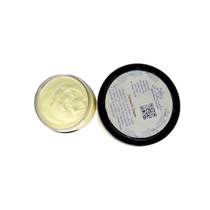 May include: Two jars of Tarmarle Cream, one open, showing a creamy yellow substance. The other jar is closed, with a black lid featuring white text and a QR code. The label lists ingredients like Mango Butter, Shea Butter, and Essential Oils.
