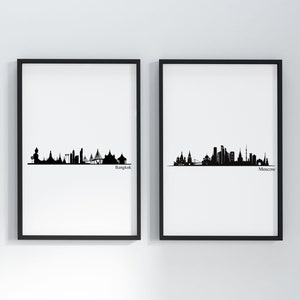 May include: Two black and white framed prints of city skylines. The left print shows the Bangkok skyline with the text "Bangkok" below. The right print shows the Moscow skyline with the text "Moscow" below.