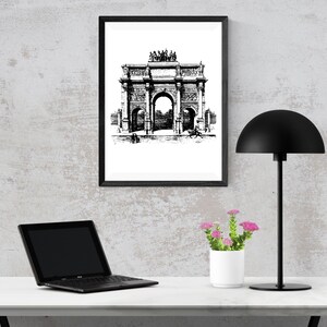 May include: Black and white line art print of an archway with a black frame, a black lamp with a dome-shaped shade, a laptop computer, and a potted plant with pink flowers on a white table.