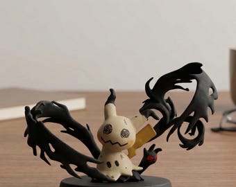 May include: A Mimikyu figurine, featuring a cream-colored body with a stitched-on face and a black, jagged tail. The figurine is set on a black base, with a red claw detail, and is likely a collectible item.