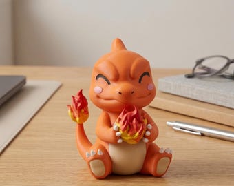 May include: An orange figurine of a cartoon character with a flame on its tail and holding a flame in its hands. The figurine has a cream-colored belly and pink cheeks. The character is sitting down with a happy expression.