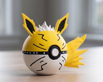 May include: A yellow and white decorative ball with black accents, featuring pointed ears and a wing-like element. The design includes black lines and a white, spiky top, resembling a cartoon character.