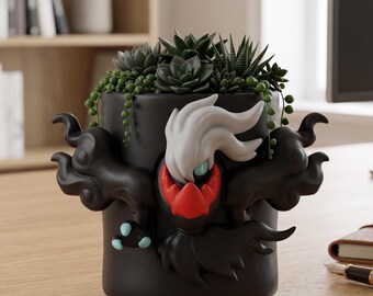 May include: Black ceramic planter featuring a stylized character design with white, red, and blue accents. The planter is filled with various green succulents. A unique decorative item for plant enthusiasts.