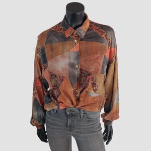 May include: A long-sleeved button-down shirt with a patchwork design in shades of brown, orange, and grey. The shirt features a collared neckline, gold buttons, and a pocket. Decorative floral patterns adorn the cuffs and collar.
